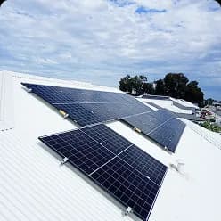 Solar panels on a white metal roof under a cloudy sky in Brabham, WA