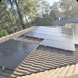 Solar panels on a tiled roof surrounded by trees in Moggill, QLD